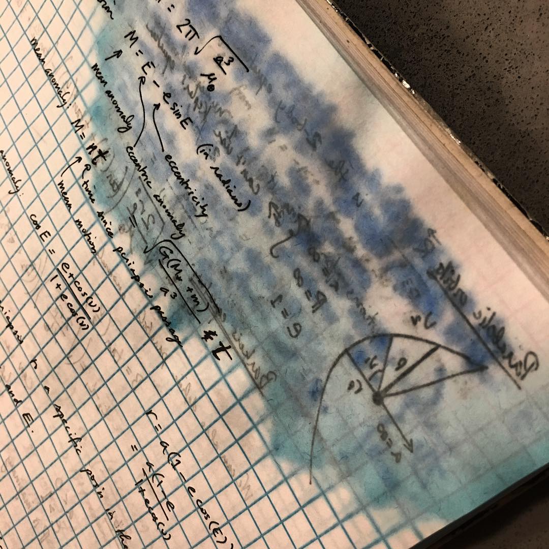 Image of a water-damaged notebook containing equations related to orbits